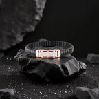 Black bracelet with rose gold clasp on a dark stone surface