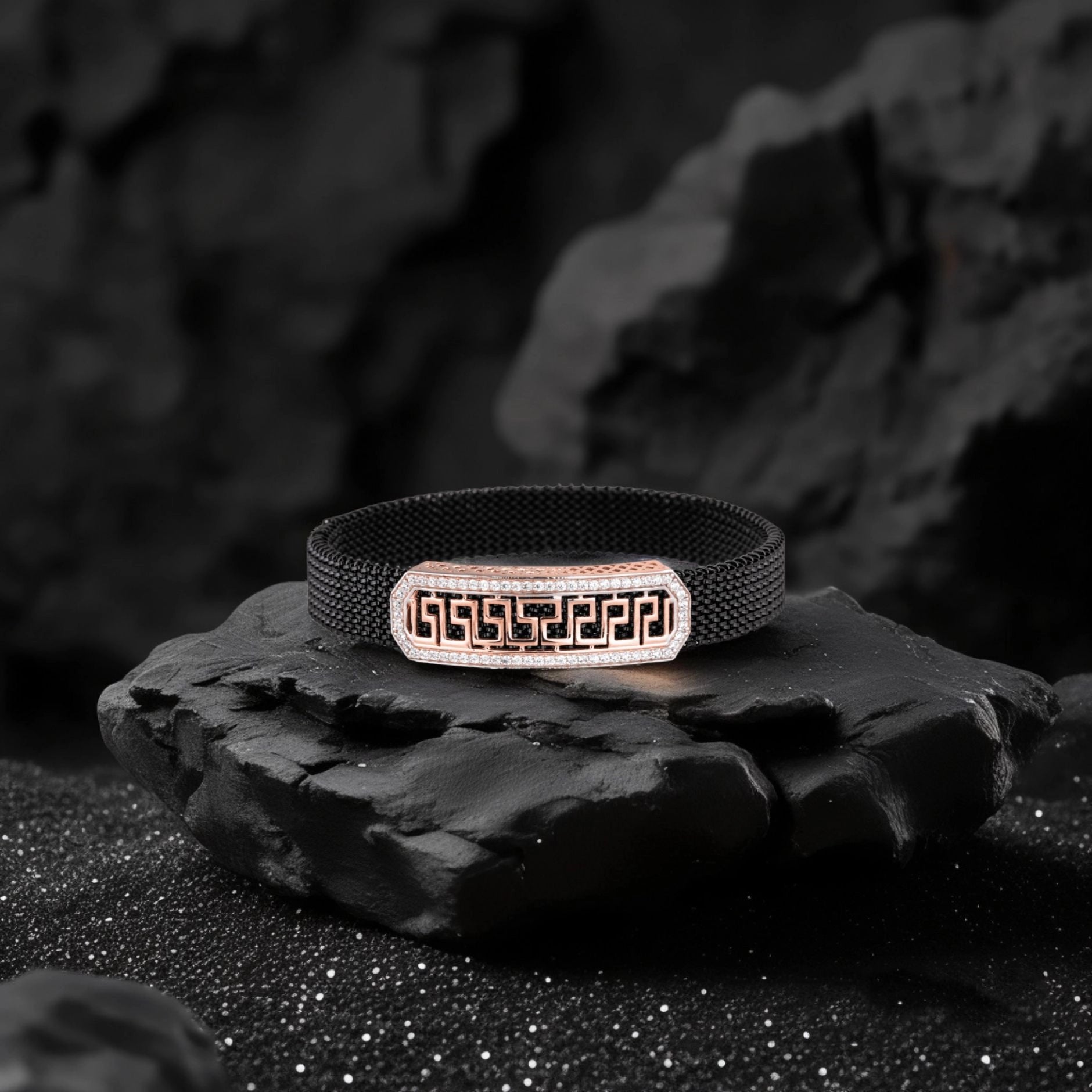 Black woven bracelet with a metallic clasp on a dark stone surface