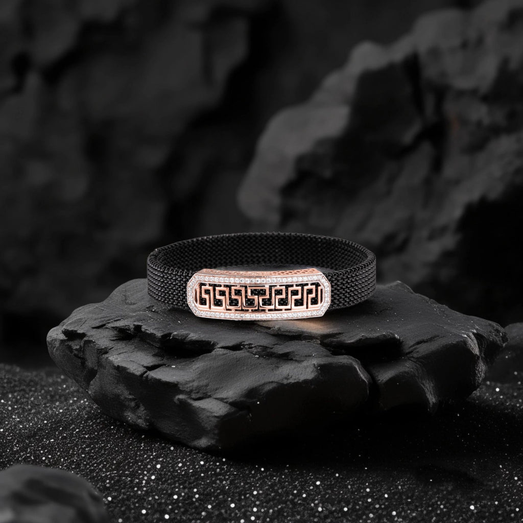 Black woven bracelet with a metallic clasp on a dark stone surface