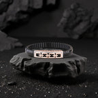 Black bracelet with a geometric design on a dark stone surface