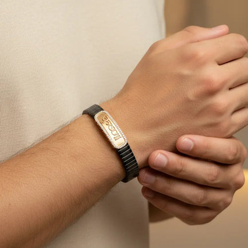 Person wearing a bracelet with a visible brand logo on a neutral background