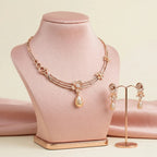 Rose gold necklace and earrings on a pink mannequin and stand against a beige background
