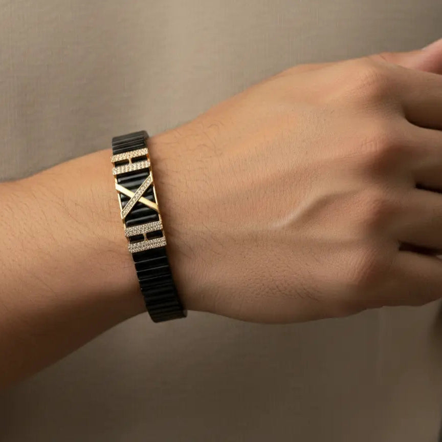 Person wearing a black and gold patterned bracelet on a neutral background