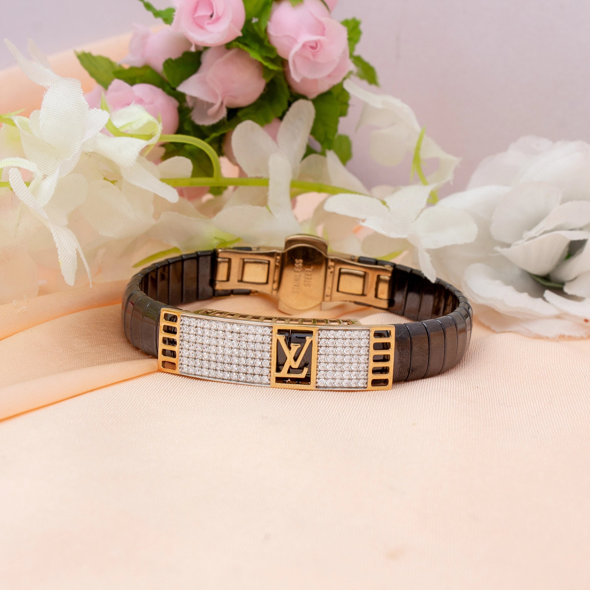 Luxury bracelet with brand logo on a pink surface with flowers