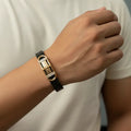 Hand wearing a black and gold bracelet with a white background