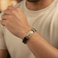Gold bracelet on a wrist with a neutral background