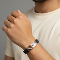 Person wearing a black and rose gold bracelet on a neutral background