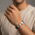 Person wearing a silver bracelet on a neutral background